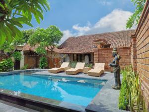 a swimming pool with a statue next to a house at Mahe Garden Inn and Villas by Kamara in Kuta