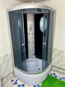 a glass shower in a bathroom with a green rug at Kayyr Guest House in Orgochor
