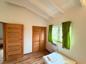 a bedroom with a bed and a window with green curtains at Domki w Wytownie k. Ustki in Wytowno
