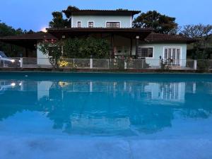 ein Haus und ein Pool vor einem Haus in der Unterkunft Sítio Paraíbuna - Fazenda Paraíbuna - Casa Campo in Paraibuna