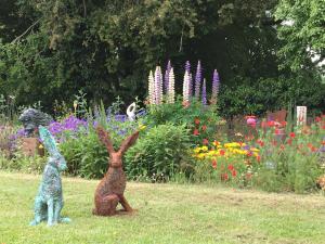 two rabbits sitting in a garden with flowers at Art House B & B in Raglan