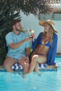 a man and woman sitting next to a swimming pool at The Bantry Bay Aparthotel by Totalstay in Cape Town