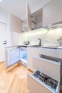 La cuisine est équipée de placards blancs et d'un réfrigérateur ouvert. dans l'établissement Near Žalgiris Arena Apartment, à Kaunas