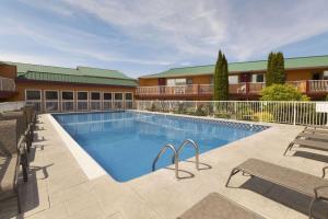 una piscina en un complejo con sillas y un edificio en Days Inn by Wyndham Penticton Conference Centre, en Penticton