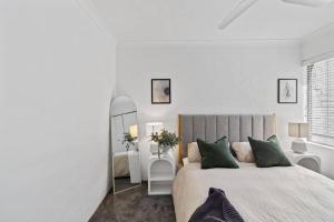 a white bedroom with a large bed and a mirror at 3br unit Stylish retreat SouthPerth in Perth