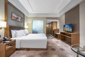 a bedroom with a large white bed and a television at Ramada Plaza Pudong Shanghai in Shanghai