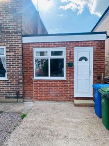 a brick house with a white door and two windows at Brand New Garage Conversion in Urmston