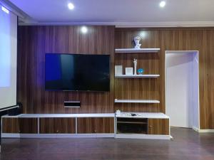 a living room with a flat screen tv on a wooden wall at Lovely 2-Bed House in Lagos in Lagos
