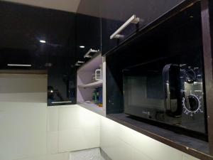 une cuisine avec des armoires noires et un four micro-ondes dans l'établissement Lovely 2-Bed House in Lagos, à Lagos