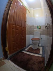 a bathroom with a wooden door and a toilet at Nyeri Nest Retreat - One Bedroom in Nyeri
