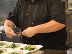 Um chef está a preparar comida numa cozinha. em ibis Montélimar Nord em Saulce-sur-Rhône