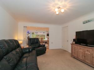 a living room with a black leather couch and a flat screen tv at Sandy Toes in Christchurch