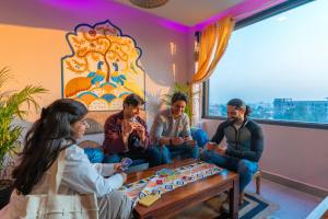 un grupo de personas sentadas alrededor de una mesa en una habitación en The Hosteller Amritsar, en Amritsar