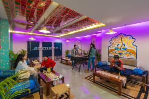 a group of people sitting in a room with purple lights at The Hosteller Amritsar in Amritsar