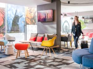 une femme qui traverse une pièce avec des chaises et des tables dans l'établissement ibis Lyon Caluire Cité Internationale, à Caluire-et-Cuire