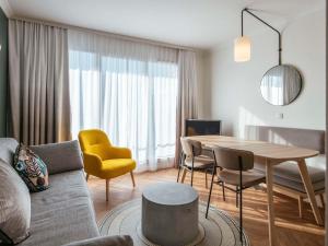 a living room with a table and a yellow chair at Aparthotel Adagio Paris Buttes Chaumont in Paris