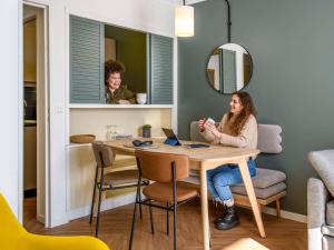 een vrouw aan een tafel met een laptop bij Aparthotel Adagio Paris Buttes Chaumont in Parijs