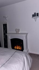 a fireplace in a white room with a bed at Chez Chris et Gildas in Gilly-sur-Isère