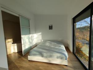 1 dormitorio con cama y ventana grande en Au calme, belles prestations, en Saint-Pierre-de-Chandieu