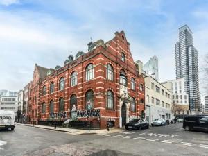 a large red brick building on a city street at Pass the Keys Spacious flat in Shoreditch in London