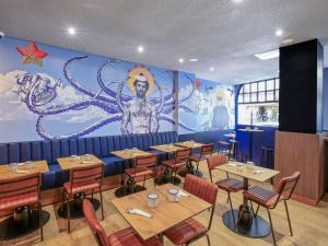 ibis Styles Saint Malo Centre Historique في سان مالو: مطعم بطاولات وكراسي وجدارية