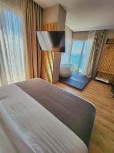 a bedroom with a bed and a bathroom with a tub at Hotel Apollon Sarande in Sarandë