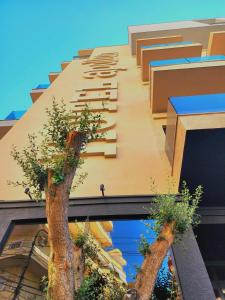 zwei Bäume an der Seite eines Gebäudes in der Unterkunft Hotel Apollon Sarande in Sarandë