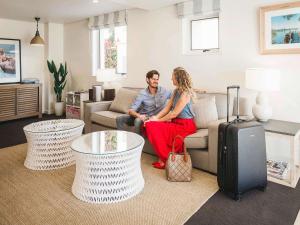 a man and woman sitting on a couch in a living room at The Sebel Noosa in Noosa Heads