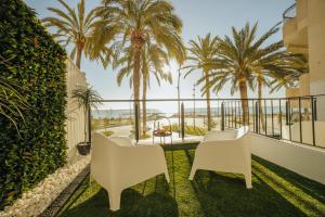 einen Balkon mit 2 Stühlen und Palmen in der Unterkunft HOSTAL LUXURY NIT I DIA in Altea