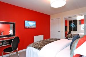 ein rotes Schlafzimmer mit einem Bett und einem TV in der Unterkunft Trendy apartment a short drive from Aberdeen City in Aberdeen