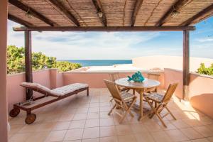 un patio con mesa, sillas y el océano en Cala Flores Gem - Sea View Lovely Apartment en Porto Cervo