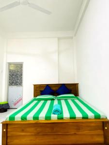 a bedroom with a green and white bed with blue pillows at Royal Homes and Wellness Center in Kurunegala