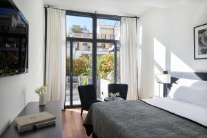 a bedroom with a bed and two chairs and a window at Majestic Hotel & Spa Barcelona GL in Barcelona