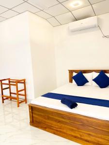 Un dormitorio con una cama con almohadas azules y una silla en Royal Homes and Wellness Center en Kurunegala