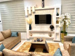 a living room with a couch and a tv at Kemc Apartment in Ashalebotwe