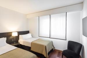 una camera d'albergo con due letti e una sedia di Majestic Hotel & Spa Barcelona GL a Barcellona