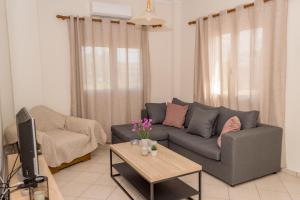 a living room with a couch and a tv and a table at Olivia House -BY APOKORNAS VILLAS in Káïna