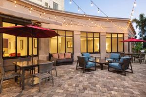 patio z krzesłami, stołami i parasolami w obiekcie Hilton Garden Inn Palm Coast Town Center w mieście Palm Coast