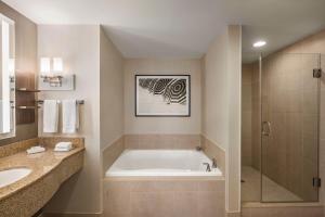 a bathroom with a tub and a sink and a shower at Hilton Garden Inn Palm Coast Town Center in Palm Coast