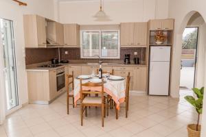 a kitchen with a table and chairs and a refrigerator at Olivia House -BY APOKORNAS VILLAS in Káïna +34 photos