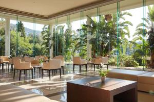 - un restaurant avec des tables, des chaises et de grandes fenêtres dans l'établissement Barceló Hydra Beach, à Thermisía