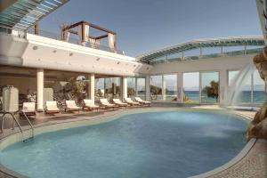 une grande piscine avec des chaises et un bâtiment dans l'établissement Barceló Hydra Beach, à Thermisía