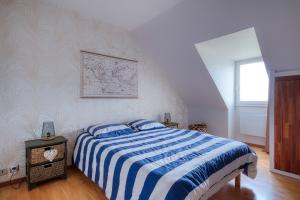 a bedroom with a bed with a blue and white striped blanket at Soleil du Crouesty - garage et piscine partagée in Arzon