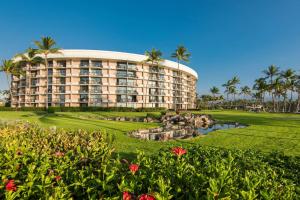 a resort building with palm trees in the background at Hilton Grand Vacations Club Ocean Tower Waikoloa Village in Waikoloa