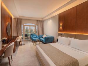 um quarto de hotel com uma cama e uma cadeira em Mövenpick Hotel Cairo - Media City em Cidade 6 de Outubro
