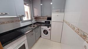 una cucina bianca con lavatrice e lavandino di Marazul Orangecosta a Peñíscola