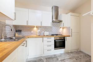 una cocina blanca con armarios blancos y fregadero en The Tower Bridge Apartment en Londres