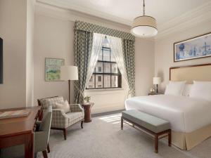 a hotel room with a bed and a desk and a window at Raffles London at The OWO in London