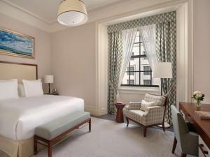 a bedroom with a bed and a desk and a window at Raffles London at The OWO in London