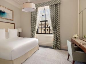 a hotel room with a bed and a window at Raffles London at The OWO in London